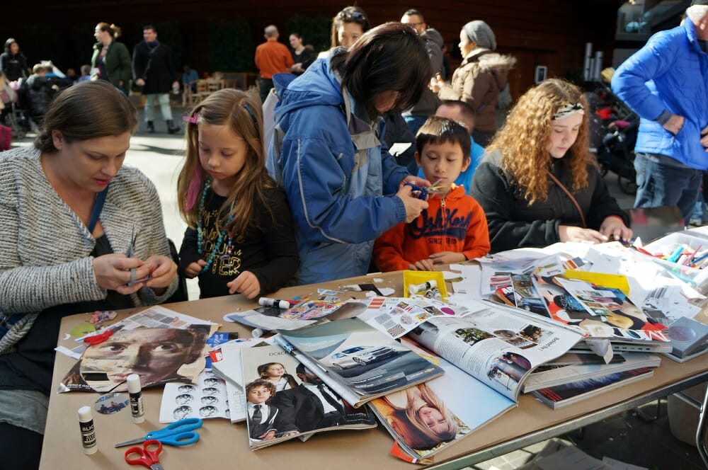 A crowd of children work on collaging crafts at a table