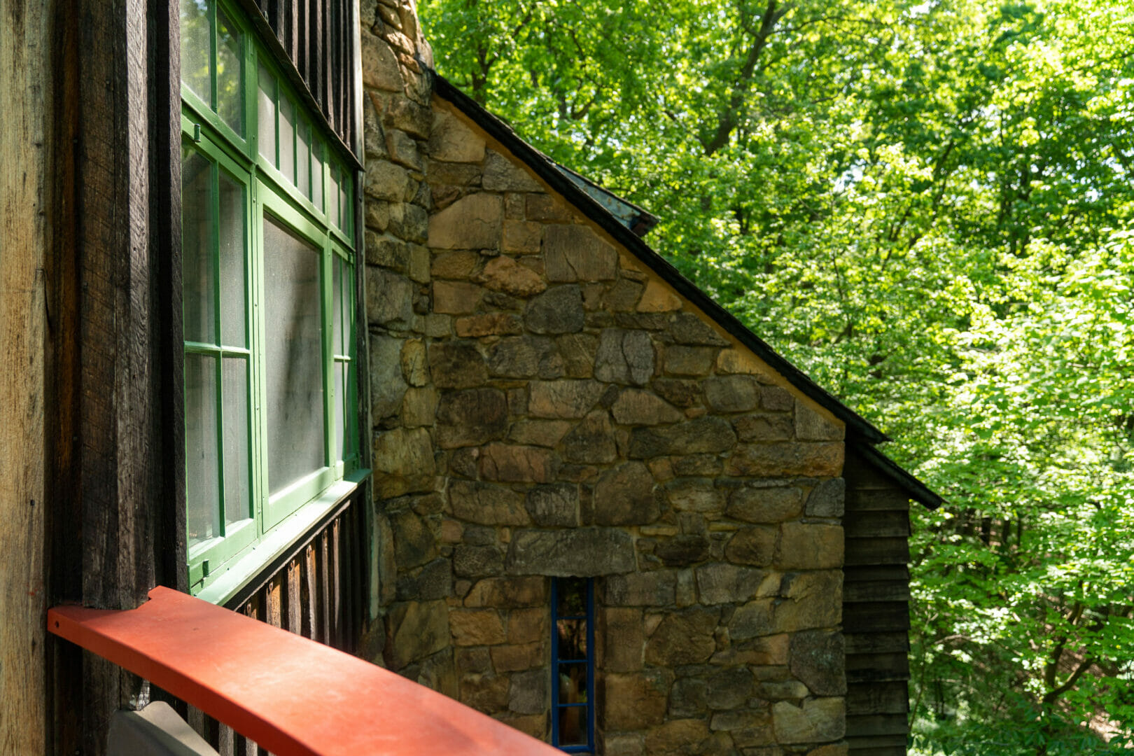 red railing of deck in bottom left with stone wall of studio in the distance