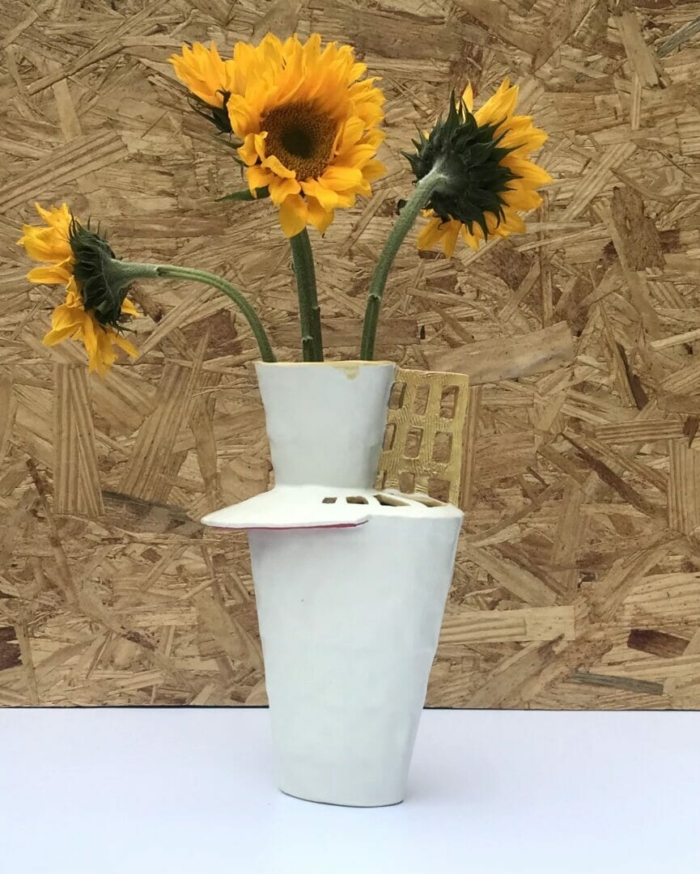 tall and narrow ceramic vase with yellow grid and turquoise top, holding yellow sunflowers