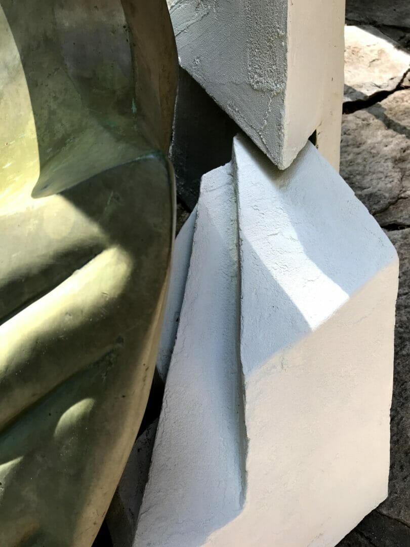 details of a bronze pelican sculpture's shoulder and wing paired closely with abstract, angular white forms