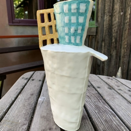 tall and narrow ceramic vase with yellow grid and turquoise top, on Esherick's deck table