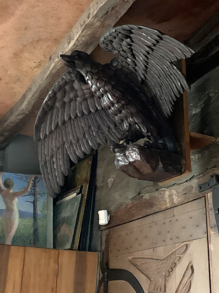carved wooden eagle with wings outstretched on a perch above loading doors
